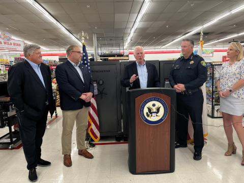 Photo of Rep. Thompson speaking behind a podium with a gun safe behind him